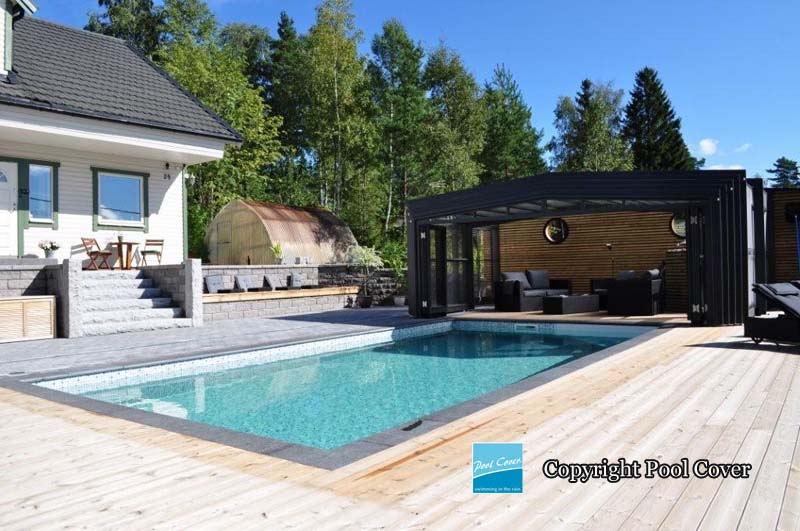 Un abri de piscine haut avec des pans droits noirs pour recouvrir la piscine extérieure d'une maison d'un particulier