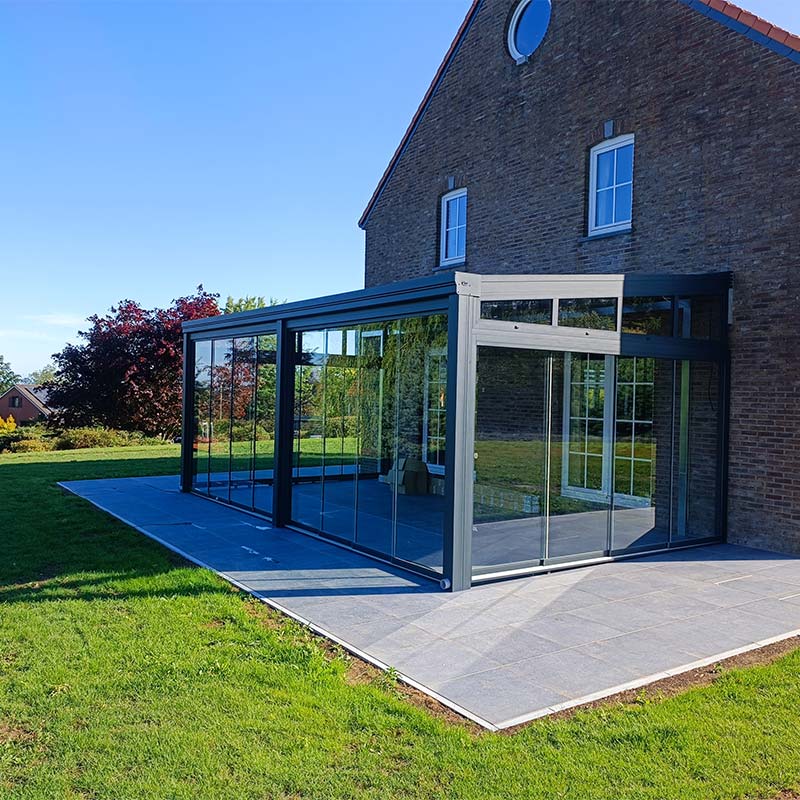 Pergola vitrée accolée à une grande maison